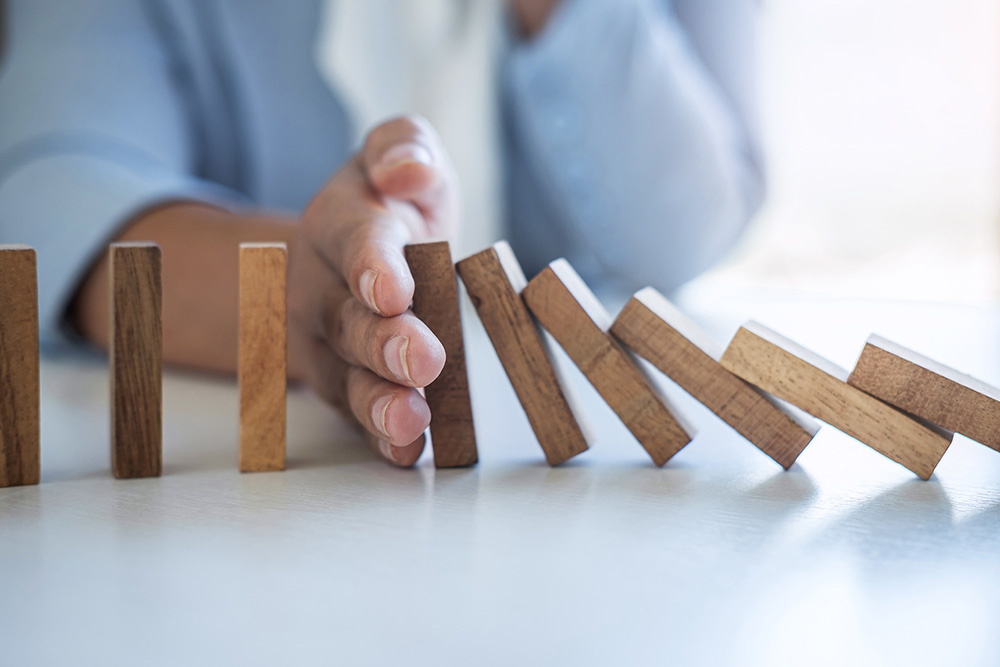 Risk and Strategy in Business, Image of hand stopping falling collapse wooden block dominoes effect from continuous toppled block, prevention and development to stability.