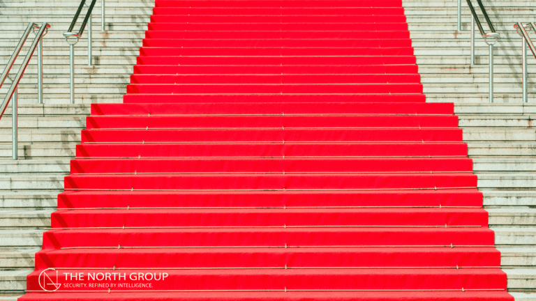 Wide staircase covered with a bright red carpet, flanked by metal railings, with "The North Group" logo at the bottom left corner.