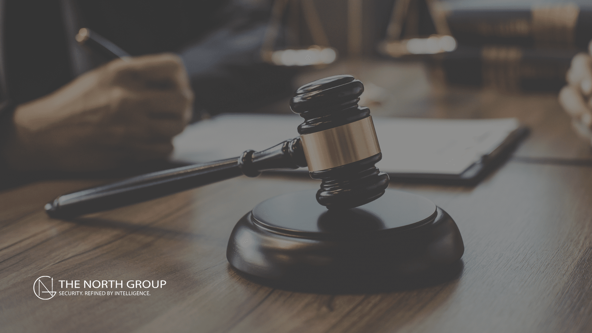 A judge’s gavel and sound block on a desk, with legal documents hinting at a UnitedHealth Shareholder Lawsuit and two people’s hands partially visible in the background. The North Group logo appears in the corner.