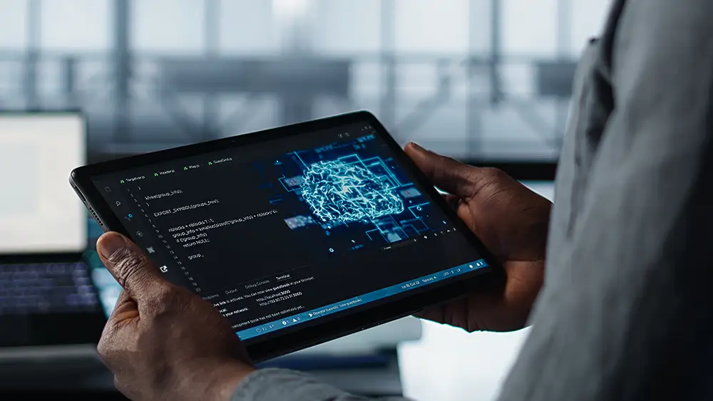 Person holding a tablet displaying code and a digital illustration of a brain, suggesting artificial intelligence or machine learning development.